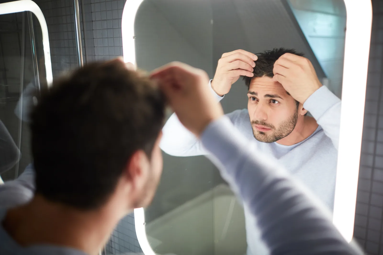 Mann untersucht Haarausfall im Spiegel